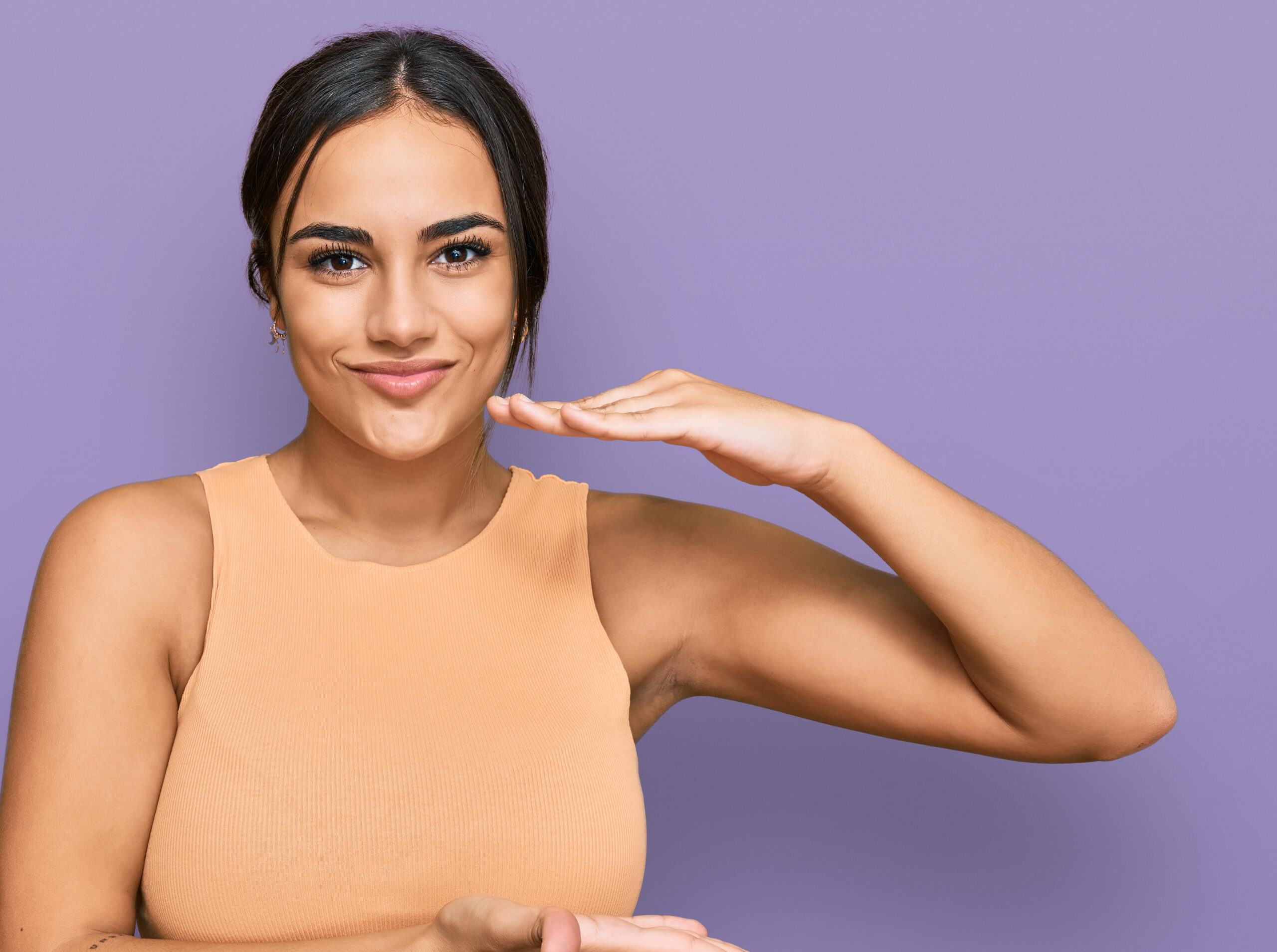 Young brunette woman wearing casual clothes gesturing with hands showing big and large size sign, measure symbol. smiling looking at the camera. measuring concept.